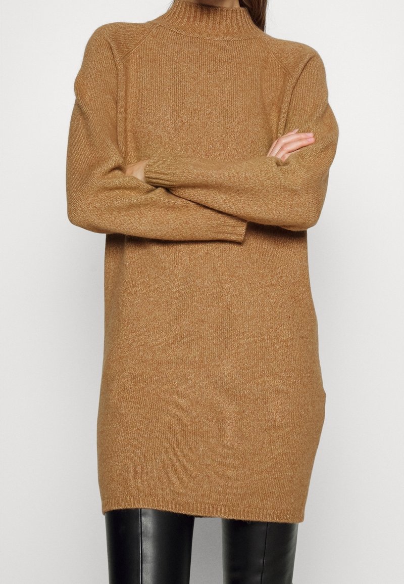 Pletený rolák v teplé béžové, s volnějším střihem, s žebrovanými manžetami a lemem, vyrobený z měkké tkaniny s jemnou strukturou.