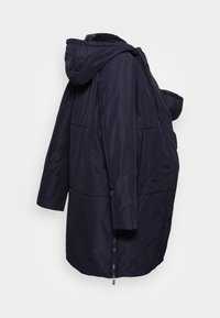 Chaqueta acolchada con capucha de color azul marino, con cierre de cremallera y ajuste oversize. Presenta una textura suave y detalles en la costura de los hombros.