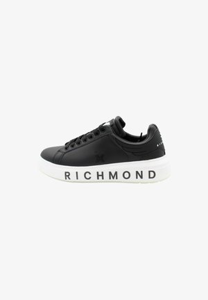 Baskets en cuir noir avec semelle en caoutchouc blanc, arborant le logo "RICHMOND" sur le côté et des coutures contrastées. Design basse avec bout rond.