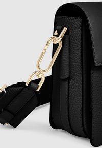 Svartr läderväska med en texturerad yta. Har en kedja i guldton och ett justerbart band med metallaccenter.