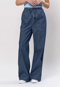 Pantaloni largi din denim albastru închis, cu talie elastică și detaliu cu șnur. Prezintă o textură netedă și o croială lejeră.