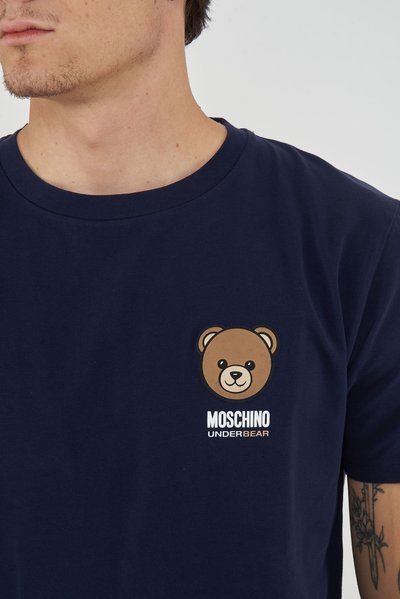 Close-up of person wearing navy blue t-shirt with a small teddy bear graphic and "MOSCHINO UNDERBEAR" text on the chest.