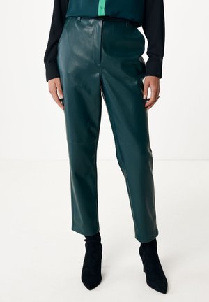 Pantalons en cuir teal avec une texture lisse, taille haute et jambes fuselées. Associés à un haut à manches longues noir et des bottines à talons noir.