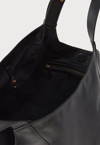 Bolsa tote preta de couro com alças de ombro, bolso interno com zíper dourado e fecho de metal no interior.