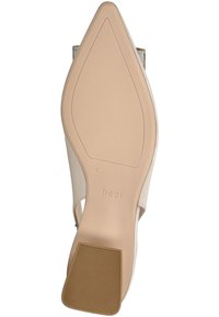 Zapato de tacón alto beige con punta afilada, parte superior de cuero suave, suela de goma texturizada y un tacón pequeño, marcado "hög."