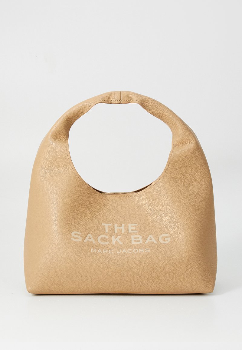 Bež nahkist käekott ringikujulise käepidemega, mille esiplaanil on reljeefne tekst "THE SACK BAG MARC JACOBS". Sile tekstuur, minimalistlik disain.