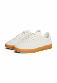 Sneaker bianchi con una parte superiore in pelle liscia, suola in gomma, dettagli perforati e lacci piatti. Caratterizzate da un profilo basso e una punta rotonda.