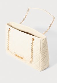 Κρεμ σακίδιο με επένδυση και χρυσές αλυσίδες, με χρυσό πλακέτα "Love Moschino" στο μπροστινό μέρος, με φερμουάρ ελαφρώς ανοιχτό.