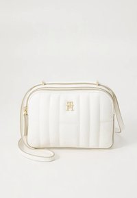 Valge tikitud risti kehakott kuldsete detailidega, millel on logodeem, tõmblukk ja reguleeritav rihm. Sile tekstuur.