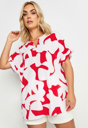 Blusa blanca con atrevidos patrones abstractos en rojo, mangas cortas y detalle en el escote en forma de llave. Tejido suave, corte relajado y costuras laterales.