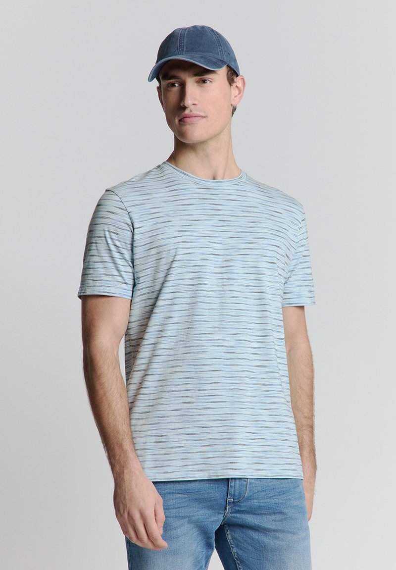 Lichtblauw T-shirt met korte mouwen, voorzien van horizontale strepen in verschillende tinten. Zachte stof, ronde halslijn, gecombineerd met een blauwe pet en denim jeans.