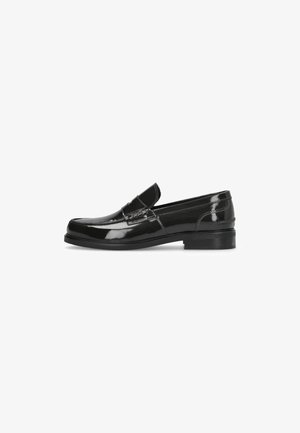 Mocasines de charol negro con un tacón bajo, que presentan una punta redondeada y costuras decorativas a lo largo de la parte superior. Diseño simple y elegante.