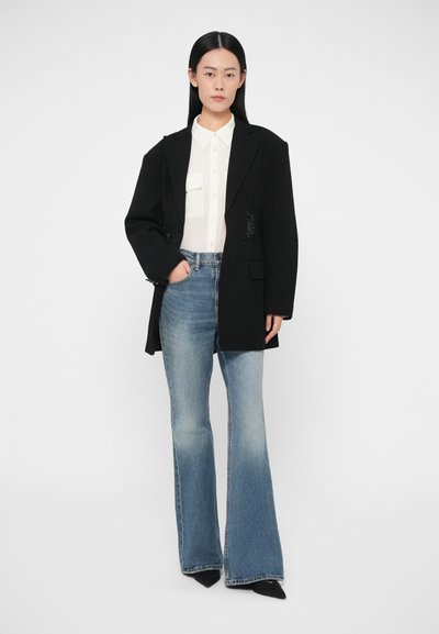 Černé nadměrné sako, bílá košile s límečkem, světle modré džíny s vysokým pasem a rozšířenými nohavicemi, černé špičaté boty. Hladká tkanina, strukturovaný střih.