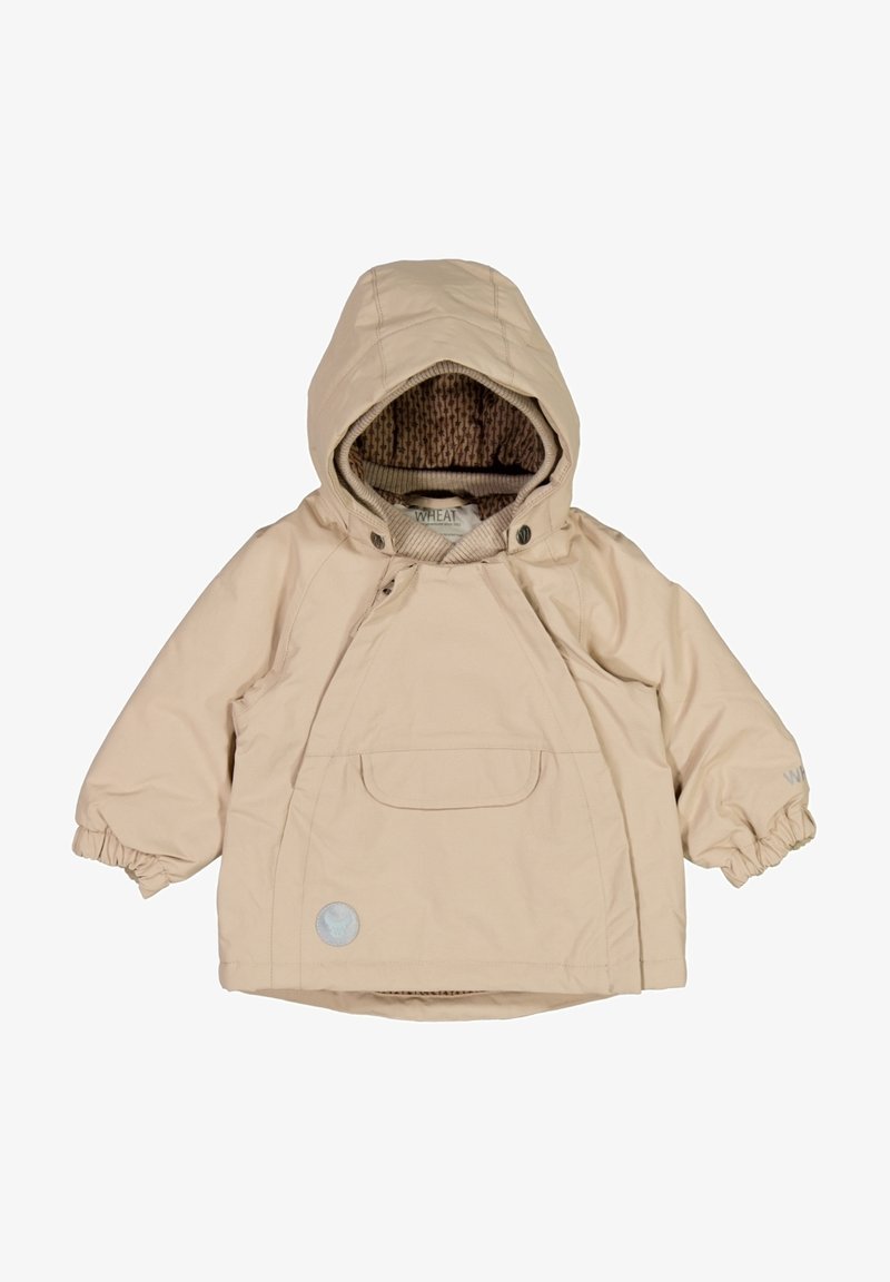 Veste légère beige avec une capuche, des poignets élastiques, une grande poche avant et une doublure brune texturée. Logo "WHEAT" près de l'ourlet.