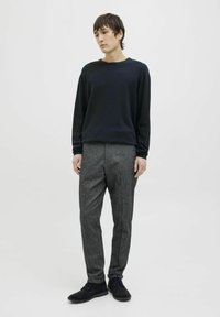 Granatowa koszula z długim rękawem, szare teksturowane spodnie i ciemne buty. Prosty design, dopasowany krój i miękka tkanina w całej odzieży.