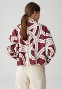 Camicia a maniche lunghe con design squadrato, marrone e crema, a motivi, e taglio cropped, caratterizzata da dettagli a linee spesse.