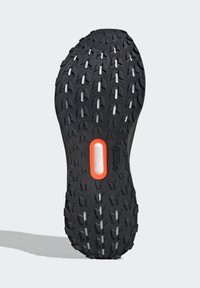 Black rubber shoe sole with aggressive tread pattern, featuring white traction lugs and an orange midsole accent. Durable and designed for grip.