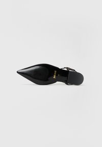 Černá dámská lodička na vysokém podpatku se špičatou špičkou a texturovanou podrážkou, s designem slingback a zlatým logem. Velikost 37 je uvedena na stélce.
