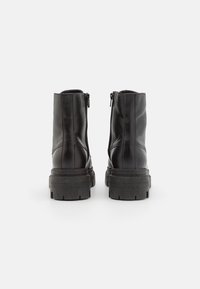 Bottines en cuir noir avec une finition lisse, zips sur les côtés et semelles en caoutchouc épaisses dotées de rainures pour une meilleure adhérence.