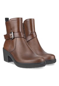 Botas de cuero marrón hasta el tobillo con un acento de hebilla y cremallera lateral, con un tacón grueso negro y suela texturizada para mayor agarre.