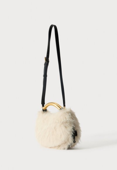 Kreminės spalvos dirbtinio kailio rankinė su išlenktu auksiniu rankenų, juodu reguliuojamu dirželiu ir minkšta tekstūra; turi užsegimą su atvartu.