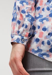 Koszula z długim rękawem w odcieniach niebieskiego, różowego i fioletowego z abstrakcyjnymi wzorami. Lekka tkanina z zapinanymi mankietami i gładką teksturą.