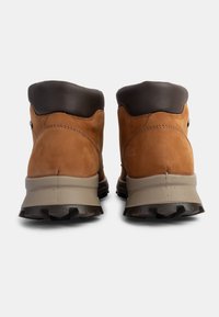 Stivaletti da trekking in pelle marrone con colletto imbottito marrone scuro, suola intermedia beige e suola esterna nera testurizzata progettata per la trazione.