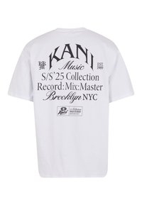 Balta medvilnė marškinėliai su per dideliu siluetu, ant nugaros esantys juodi grafikos tekstai, įskaitant "KANI Music" ir "Brooklyn NYC."