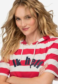 Červeno-bíle pruhovaná mikina s kapucí a krátkým rukávem, se textovým designem v námořnické modři. Elastická šňůrka na kapuci, jemná textura látky.