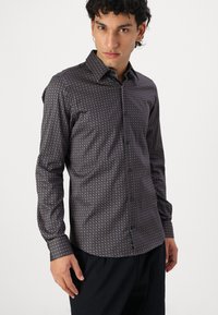 Long-sleeve button-up shirt in dark navy fabric with a geometric light blue pattern, featuring a classic collar and buttoned cuffs.