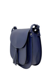 Mała granatowa skórzana torebka z klapką i dekoracyjnym chwostem, z widocznymi bocznymi sekcjami i przeszytymi uchwytami na białym tle.