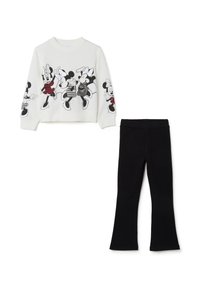 Sweatshirt blanc avec des imprimés graphiques noirs de personnages de dessin animé, associé à des leggings évasés noirs. Texture de tissu lisse sur l'ensemble.