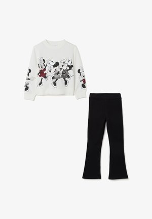 Sudadera blanca con estampados gráficos en negro de personajes de dibujos animados, combinada con leggings negros acampanados. Textura de tela suave en toda la prenda.