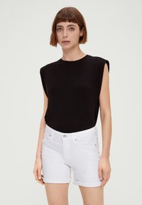 Zwarte mouwloze top met een comfortabele pasvorm, gecombineerd met witte denimshorts met opgerolde zoom en een knoopsluiting aan de voorkant.