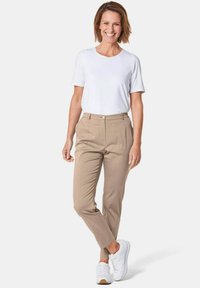 Witte t-shirt met korte mouwen gecombineerd met lichtbeige tapered broek en witte sneakers. Glad stoftextuur en een casual ontwerp.