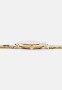 Goldfarbene Armbanduhr mit einem schlanken runden Gehäuse, flachem Glas, strukturiertem Mesh-Armband und einer Krone an der Seite für Einstellungen.