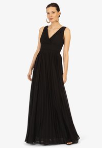 Zwarte geplooide maxi-jurk met een V-hals en brede bandjes. De stof is lichtgewicht met een vloeiende textuur en heeft een aansluitend lijfje design.