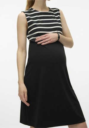 Zwangerschapsjurk met een gestreept zwart-wit bovenstuk en een effen zwarte onderkant. Mouwloos, tot op de knie, zachte stof met een gladde textuur.
