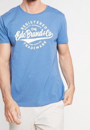 Niebieski bawełniany t-shirt z krótkimi rękawami i okrągłym dekoltem, z białym napisem graficznym "Registered Edc Brand&Co Trademark" na przodzie.