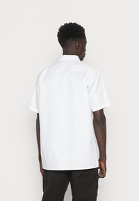 Korte mouwen, gecomma shirt in effen wit. Gemaakt van gladde stof met een rechte, ontspannen pasvorm en zonder zichtbare patronen of accenten.