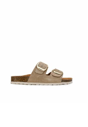 Sandalia tipo slide de ante beige con dos hebillas doradas ajustables, plantilla de corcho y suela blanca de goma texturizada.