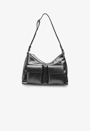 Borsa a mano in pelle sintetica nera con due tasche frontali, forma curvata, tracolla regolabile e chiusura a zip. Texture liscia con cuciture bianche.