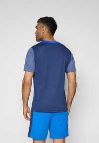 Marine performance t-shirt med korte ærmer, en blå krave og struktureret stof, parret med blå shorts med sidenstripe-detail.