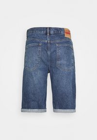 Denim shorts in keski-sininen, jossa on vaaleansininen lahje, kaksi takataskua ja ruskea nahkaviiri vyötäröllä. Klassinen muotoilu.