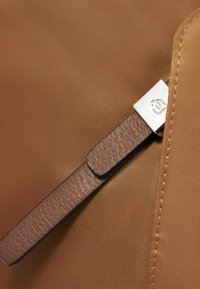 Borsa in nylon marrone con superficie texturizzata, tracolla in pelle con finitura liscia e dettaglio metallico con logo.