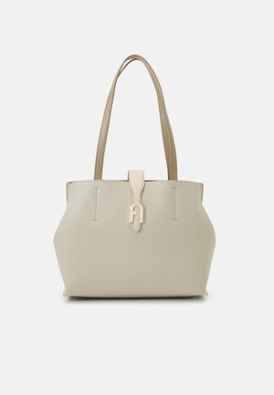 Sac fourre-tout en cuir beige avec deux poignées robustes, rabat de fermeture à l'avant, surface texturée et design minimaliste.