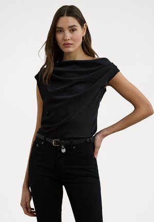 Black satin top with draped neckline, short sleeves, and smooth texture, paired with high-waisted black jeans and a thin belt with a small charm.