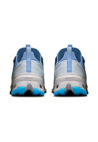 Light blue athletic shoes with a mesh upper, grey accents, and a textured sole featuring blue gripping pods. Pull tabs at the back.