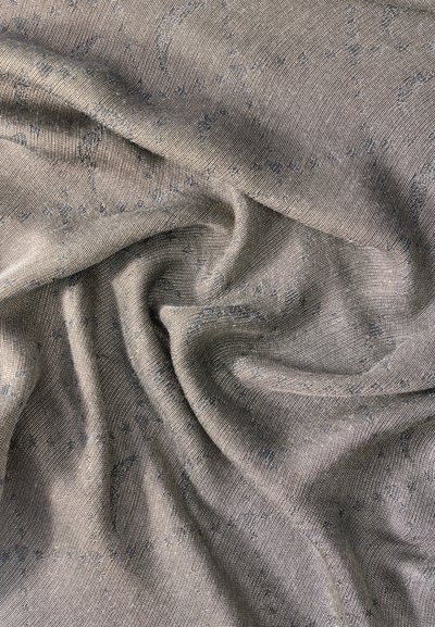 Απαλό γκρι ύφασμα με διακριτικά σχέδια πεϊсли, απαλά διπλωμένο με ορατή υφή και λεπτομέρειες λεπτής ύφανσης.