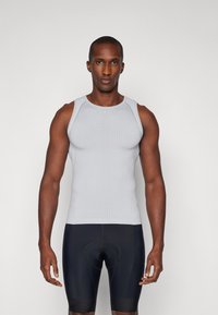 Helles graues, geripptes Sporttanktop mit rundem Ausschnitt und Schulterakzenten, kombiniert mit schwarzen, figurbetonten Shorts.